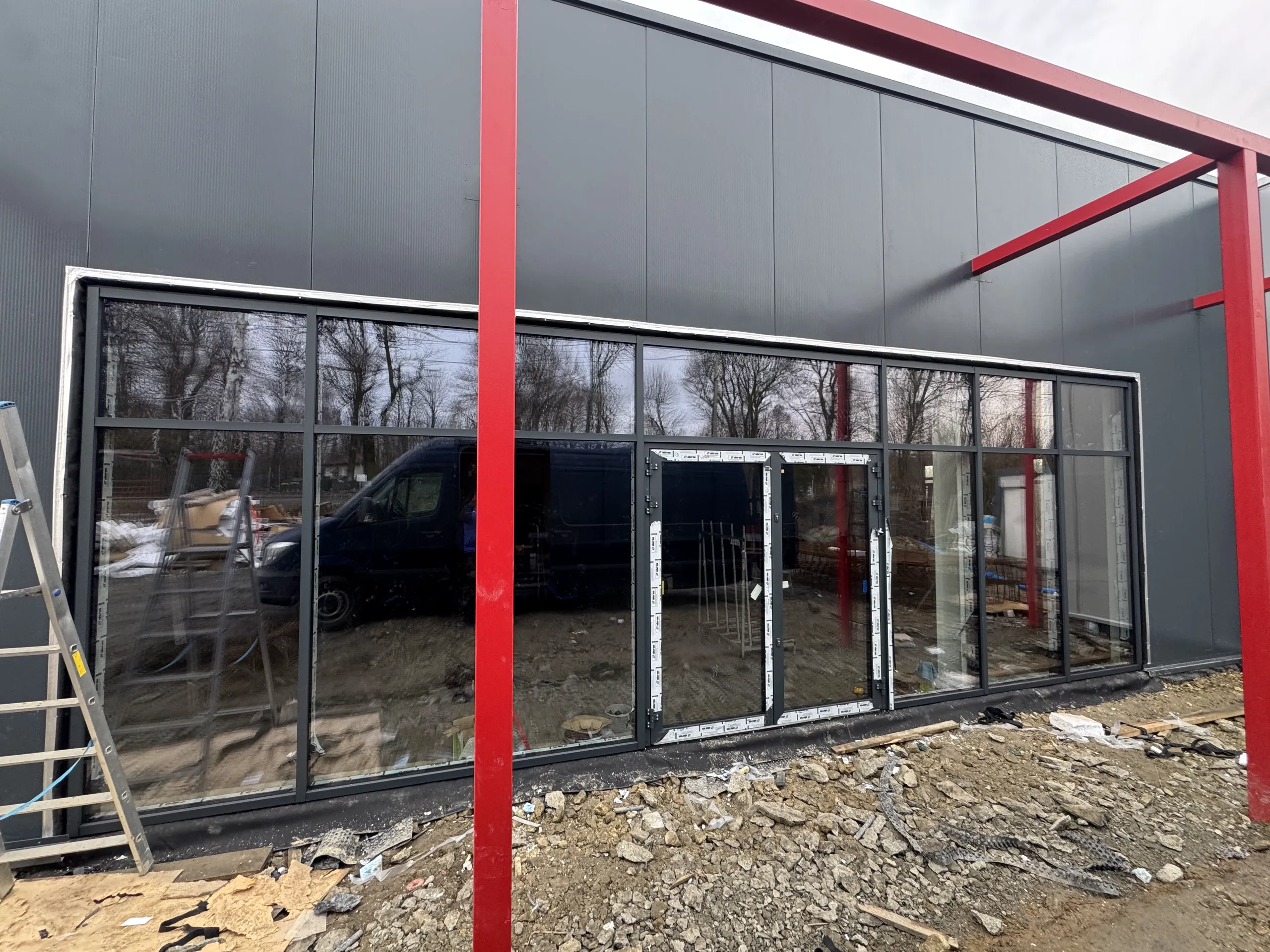 Okna aluminiowe w szklanej fasadzie w trakcie montażu na elewacji budynku z czerwonym stelażem