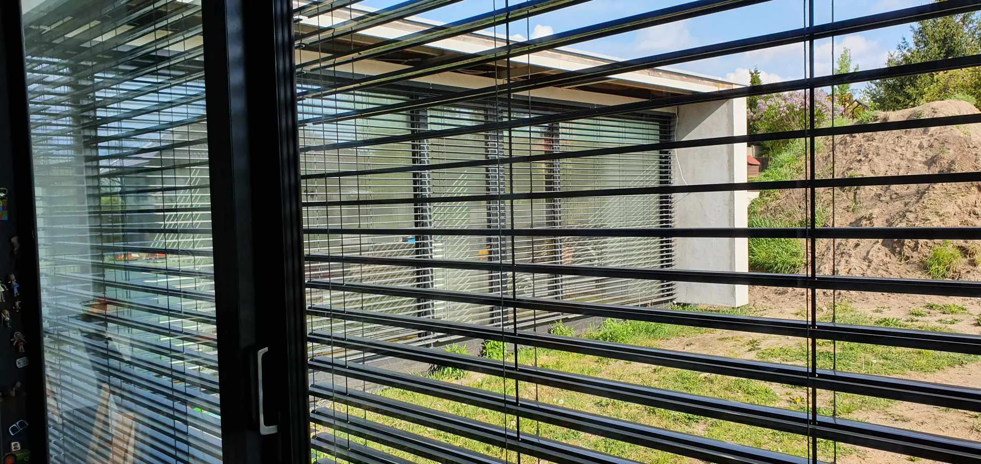 Żaluzje fasadowe z poziomymi aluminiowymi lamelami przed nowoczesnym budynkiem
